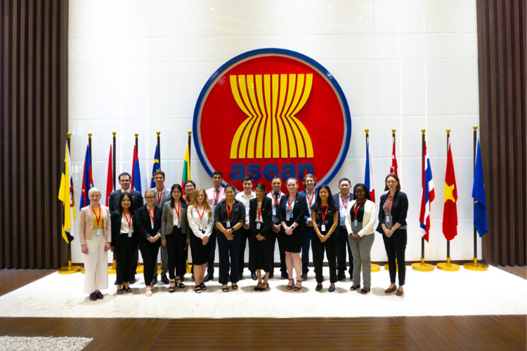 An image of a group taking a photo in front of ASEAN logo