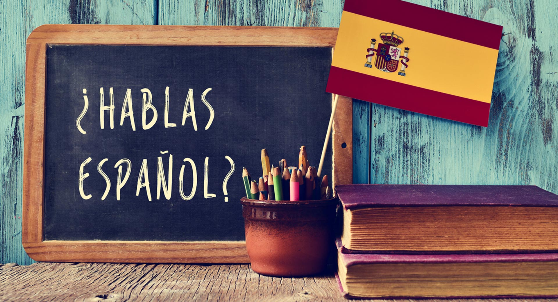 An image of the Spanish flag and a blackboard that says "Do you speak Spanish" in Spanish with some books